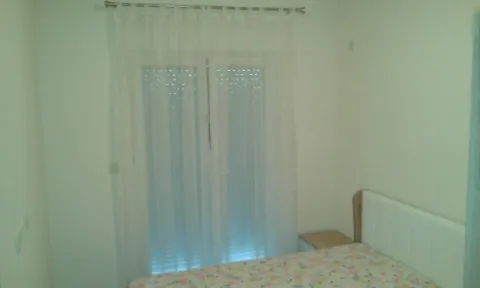 A simple bedroom featuring a bed and balcony doors with curtains. - image 4