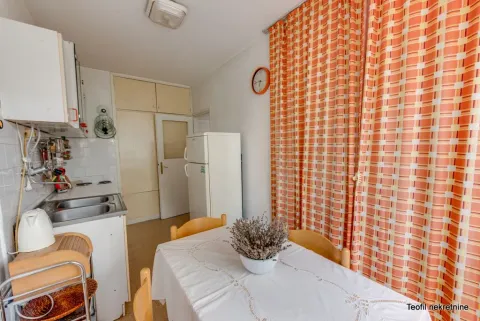 Kitchen with a dining table and a window covered with orange curtains. - image 13