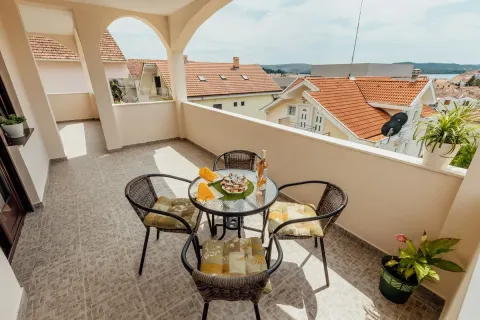 Spacious covered terrace with a table, chairs, and a view of surrounding rooftops. - image 5