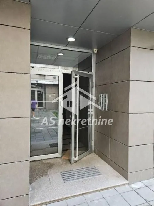 Glavni ulaz u stambenu zgradu sa staklenim vratima i popločanim stepeništem.