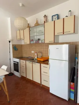 Prikaz svijetle kuhinje sa elementima u bež boji i bijelim frižiderom. - image 6