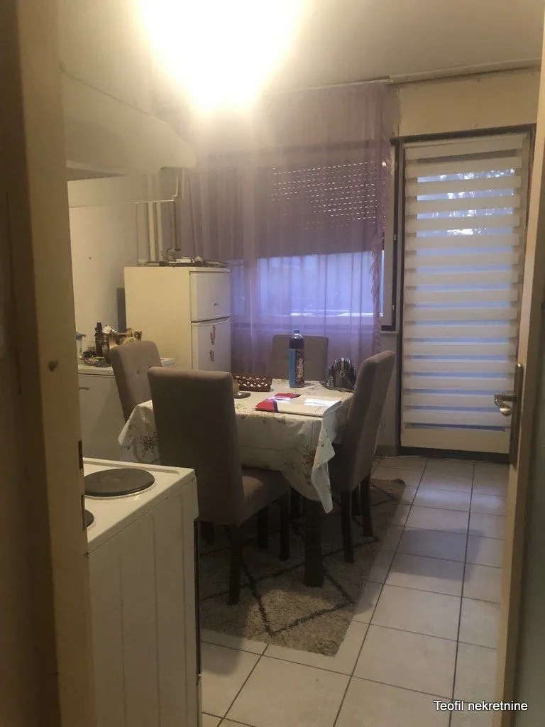 Trpezarija povezana sa kuhinjom sa stolom, stolicama i frižiderom.