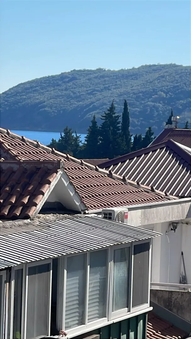 Pogled sa terase na krovove kuća, brda i more.