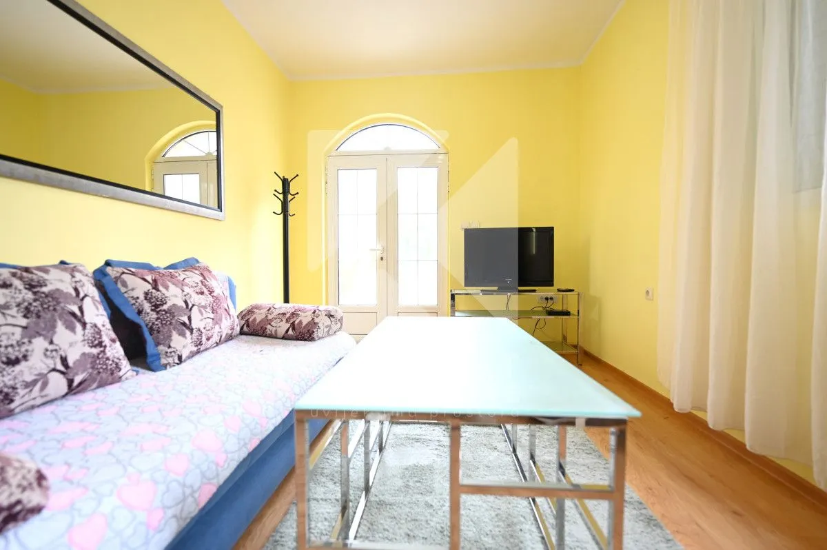 Living room with a sofa, coffee table, TV and access to the terrace.