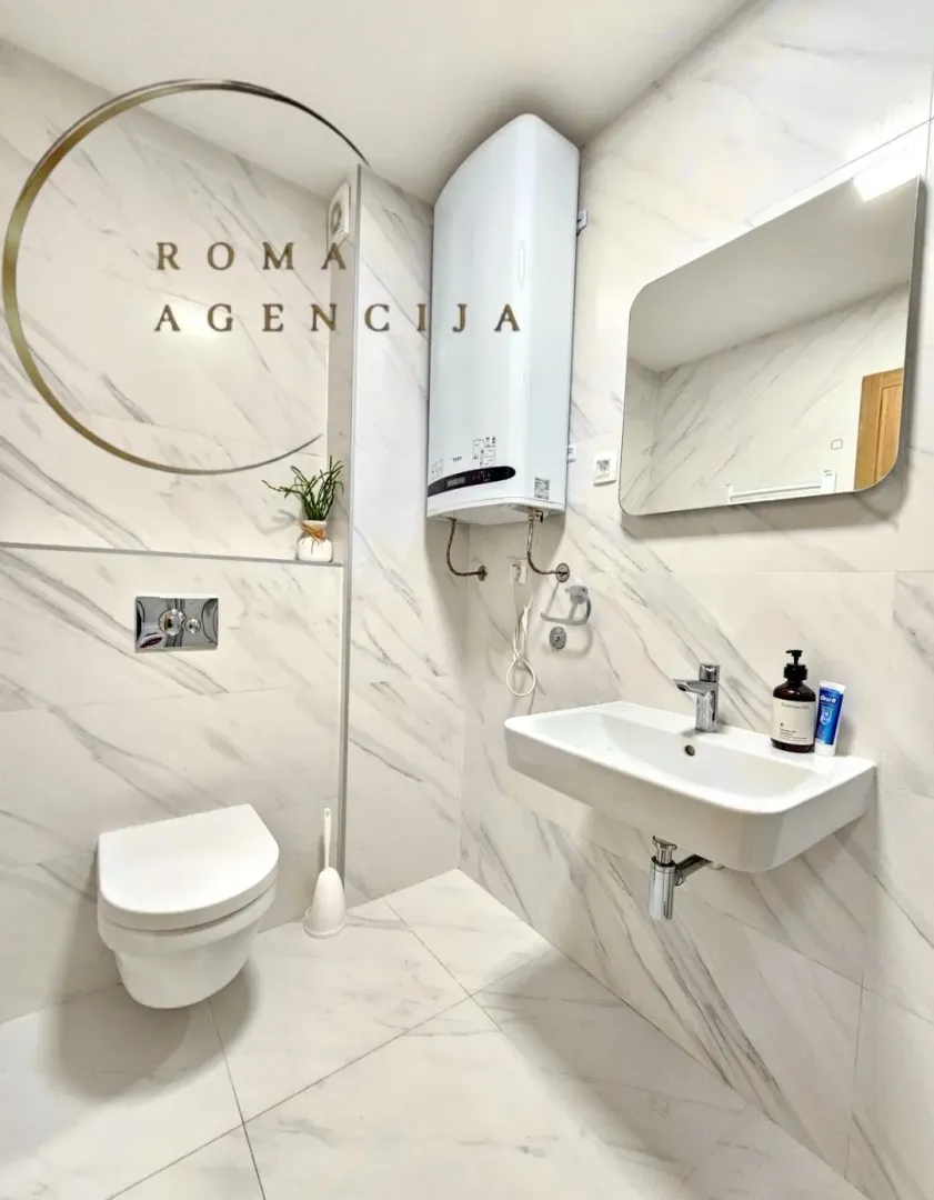 Modernly equipped bathroom with white marble tiles, washbasin, and toilet.