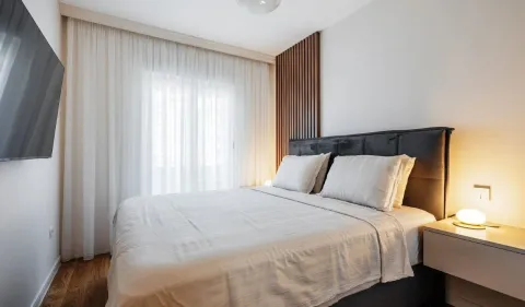 Modern bedroom with a double bed, wooden wall panel, and a wall-mounted TV. - image 6