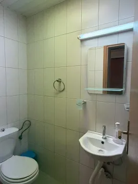 Manje kupatilo sa umivaonikom, ogledalom i toaletom obloženo keramičkim pločicama. - image 3