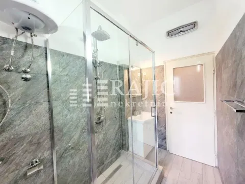 Modern bathroom with a glass shower enclosure and stone-effect tiles. - image 10
