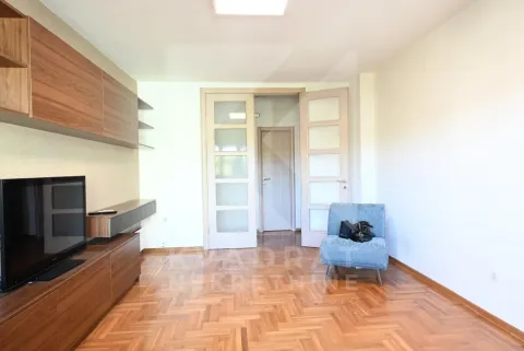 Living room with a TV, wooden furniture, and hardwood flooring. - image 3