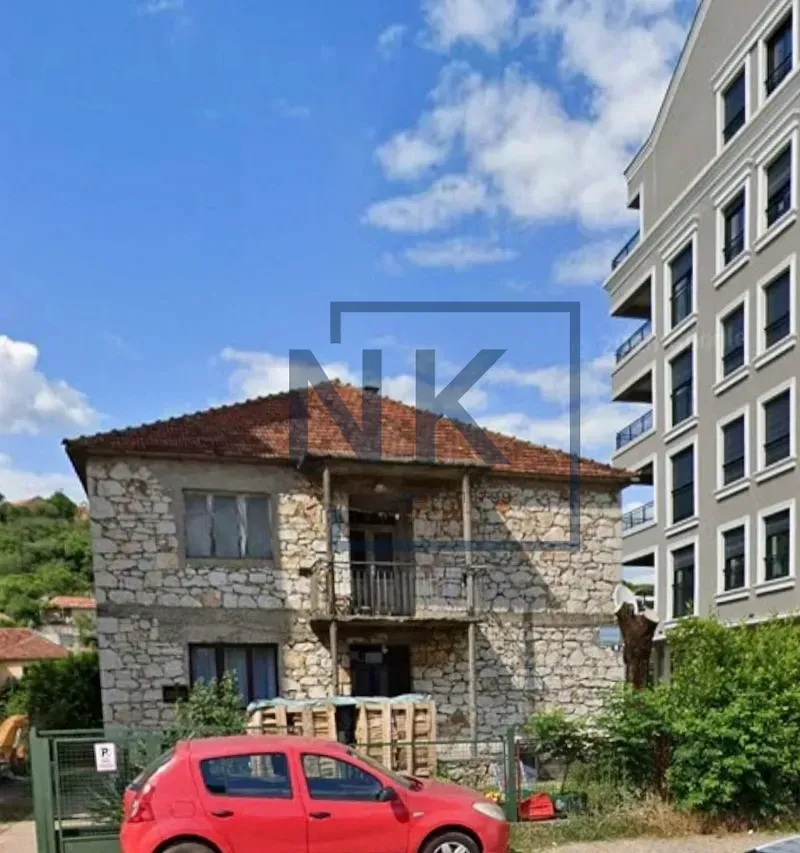View of the facade of an old stone house with a yard.