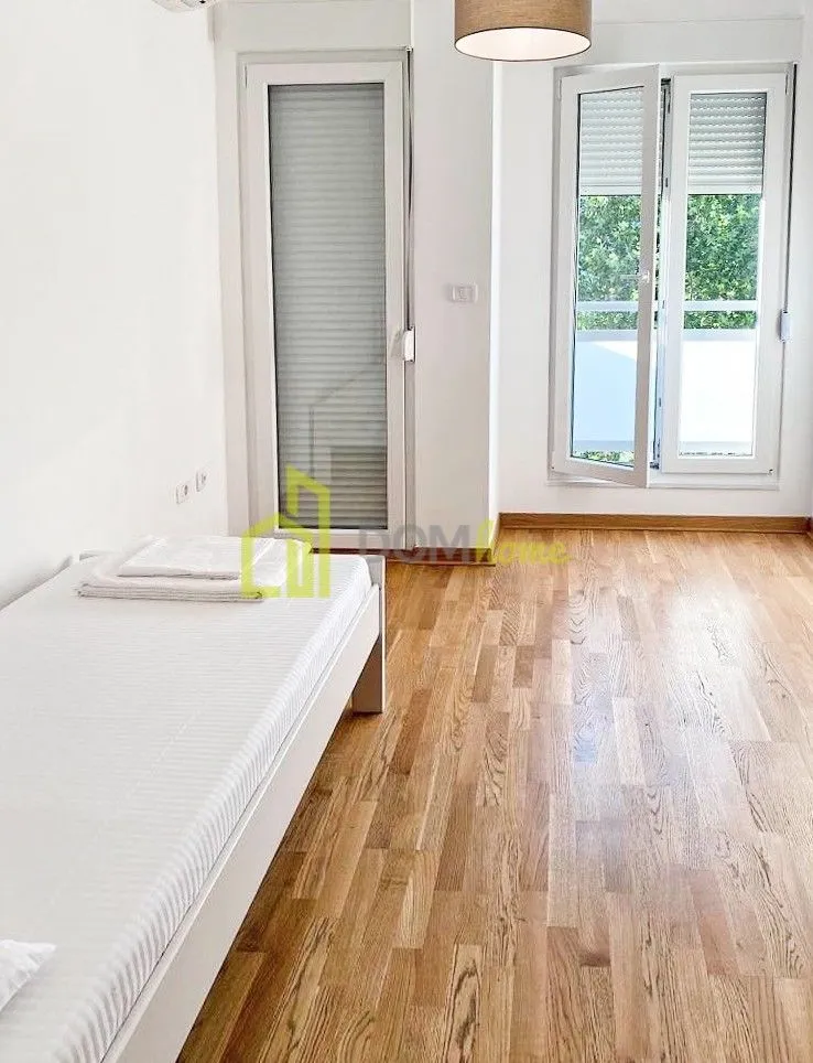 Svjetla spavaća soba sa krevetom i izlazom na balkon.