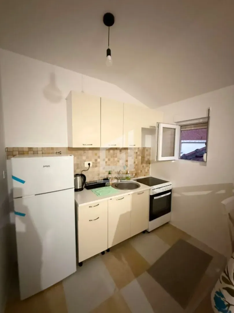 Small kitchen with white cabinets, refrigerator, and stove.