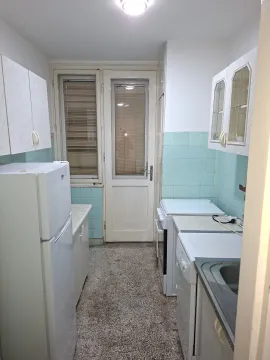 Small kitchen with white cabinets, a refrigerator, and a door leading to the terrace. - image 9