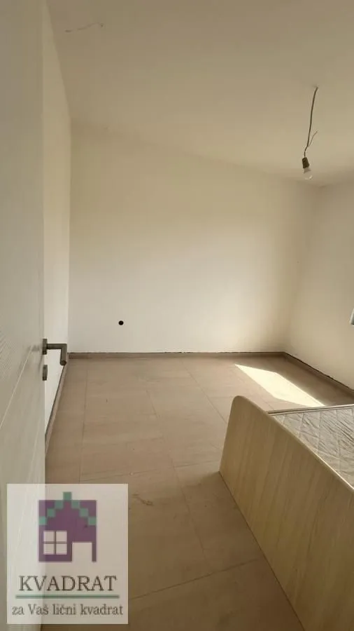 Empty room with ceramic floor tiles and part of a bed.
