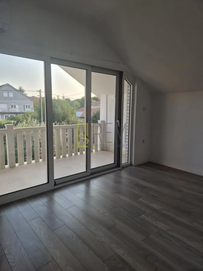 Empty attic room with access to a terrace and large glass doors.