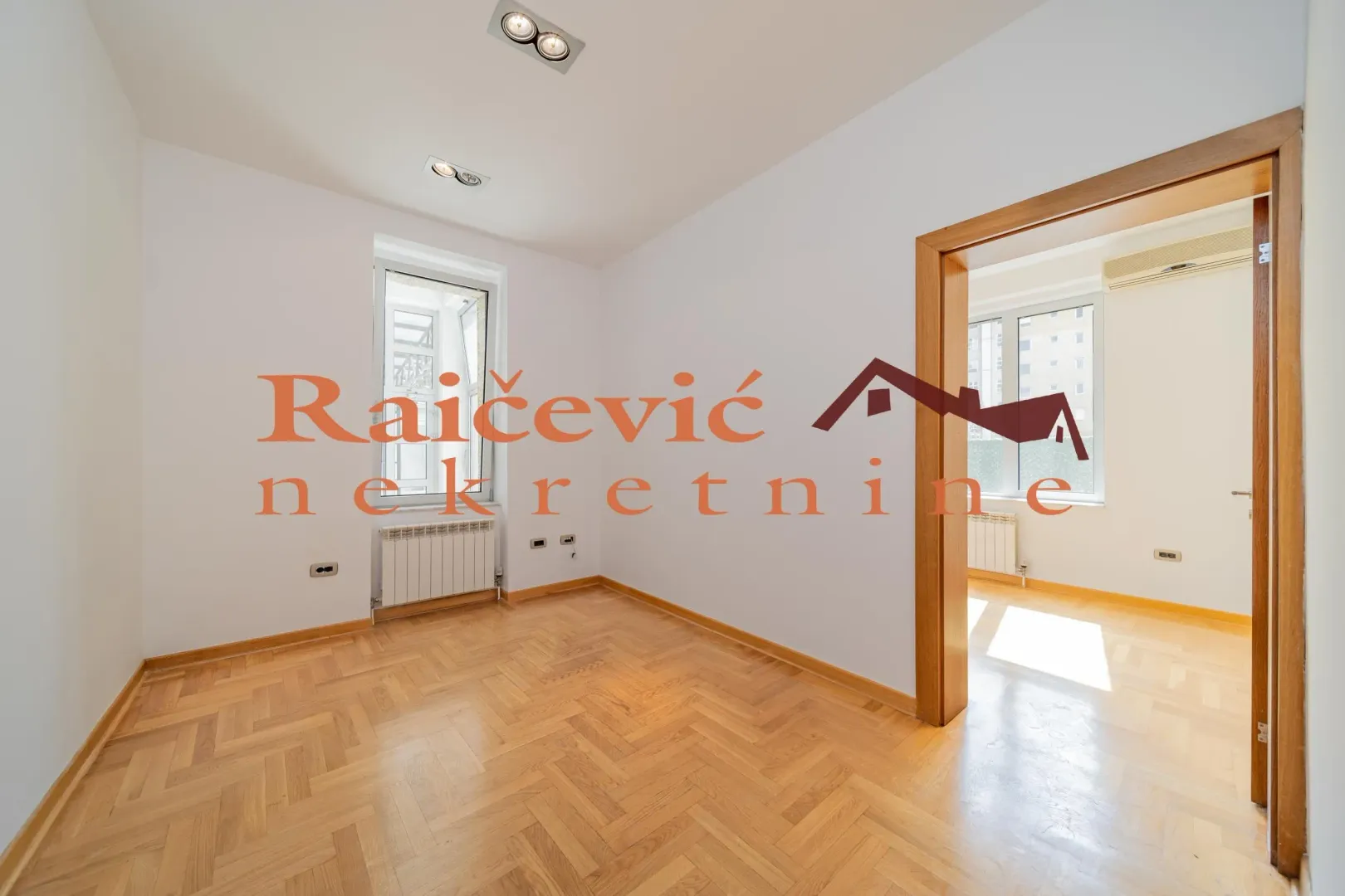 Empty room with parquet flooring and white walls.