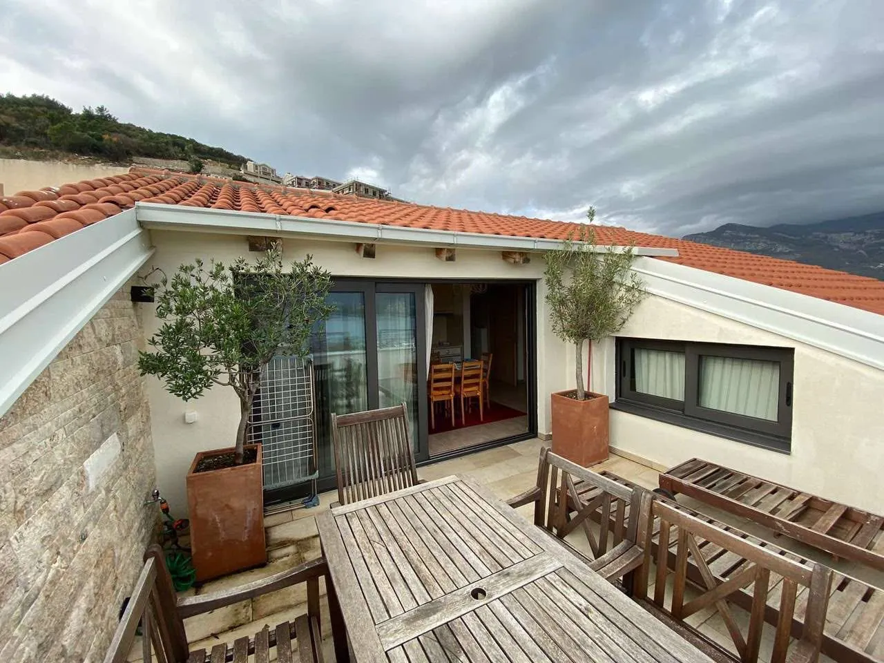 Roof terrace with outdoor seating and a view of the hills and rooftops.
