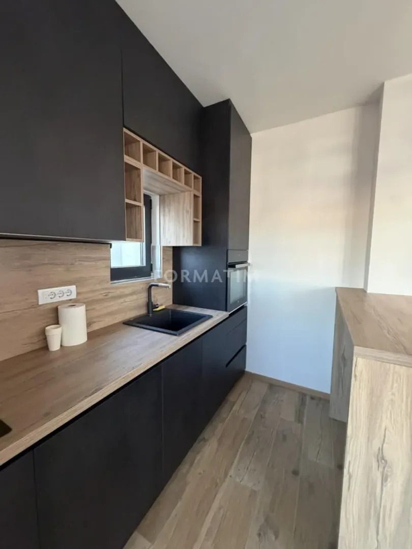 Modern kitchen with black units and a wooden countertop.