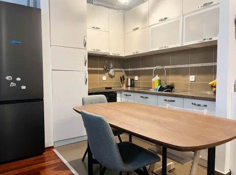 Kitchen with white cabinets and a dining table with chairs. - image 2