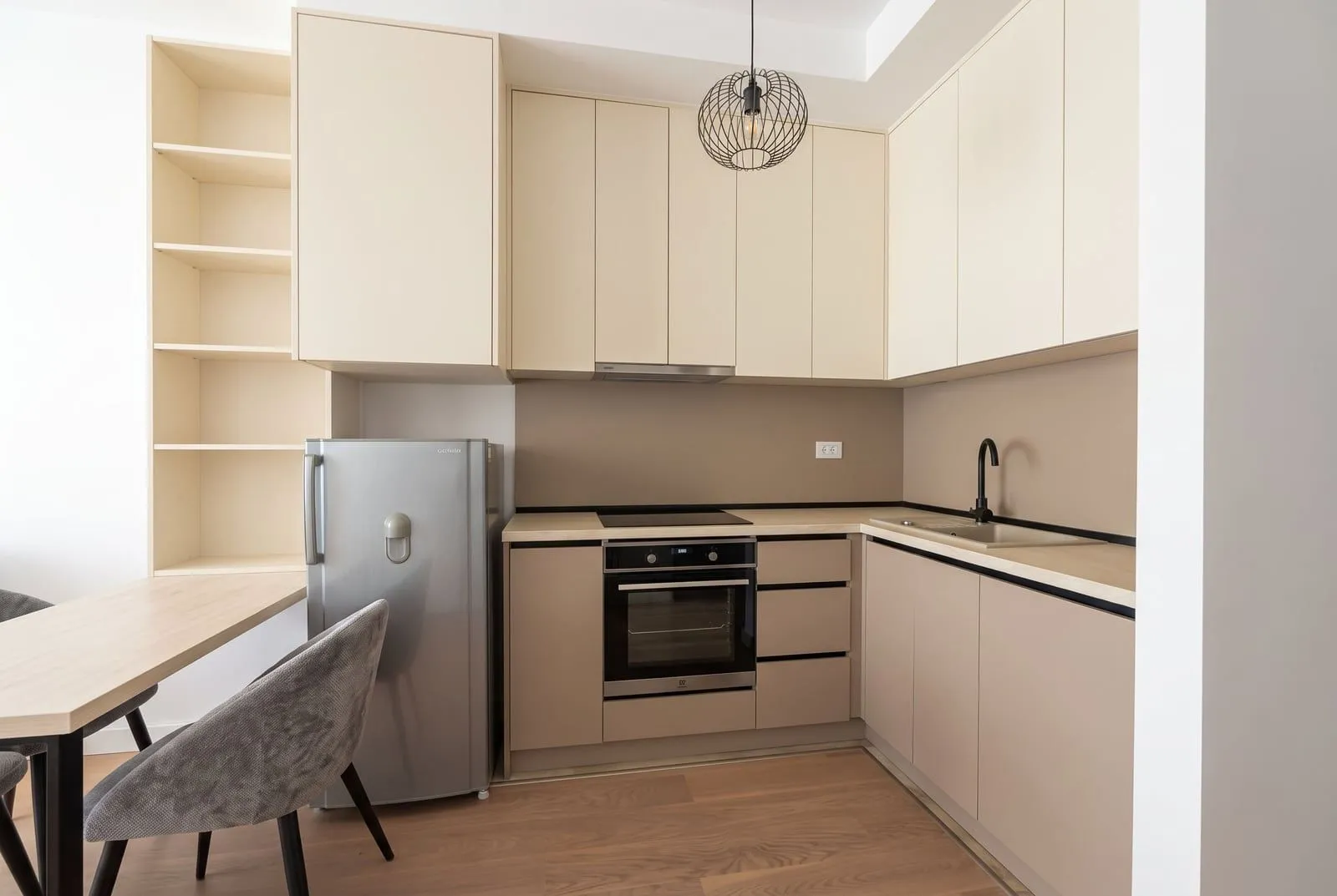 Modern kitchen with beige cabinets, built-in appliances, and a dining area.