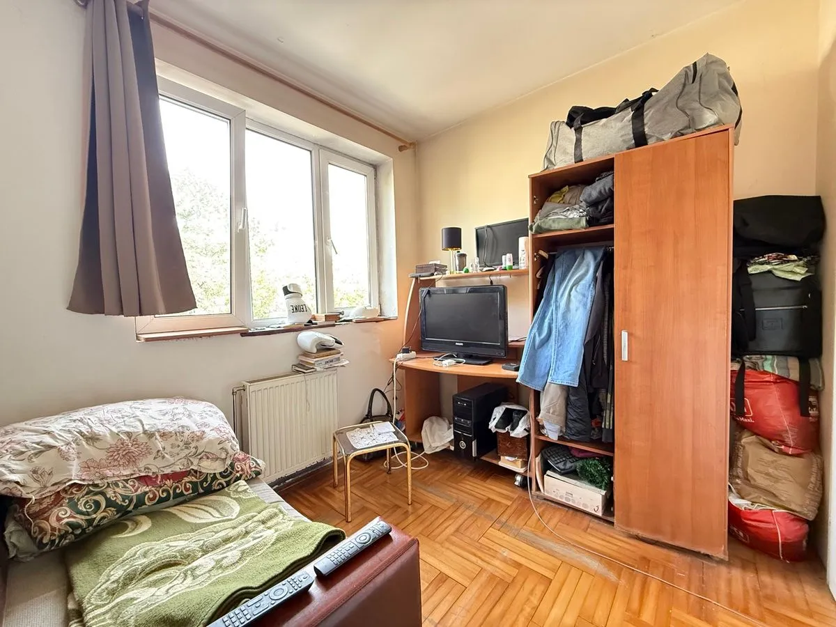 Nameštena spavaća soba sa krevetom, ormarom i radnim stolom.