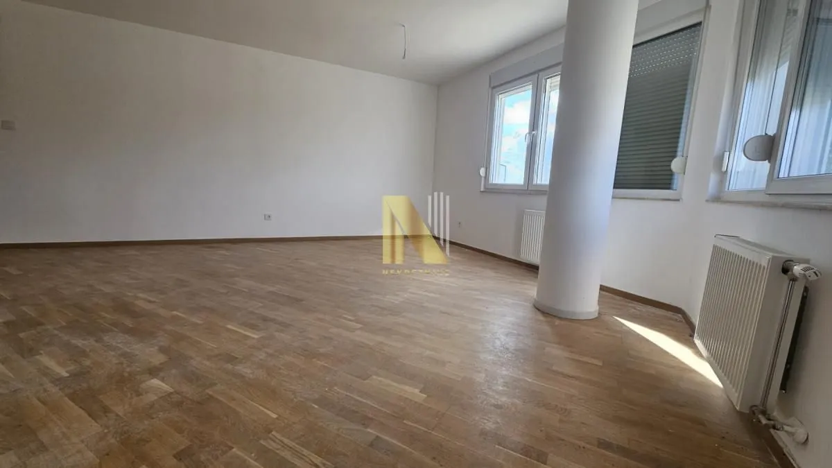Empty bright room with parquet flooring and a pillar.