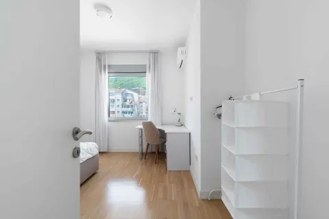 Bright bedroom with a desk and city view. - image 25