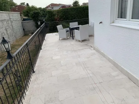 A spacious paved terrace with outdoor seating and a railing. - image 4