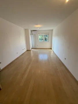 Prazna soba sa bijelim zidovima, drvenim podom i izlazom na terasu. - image 4