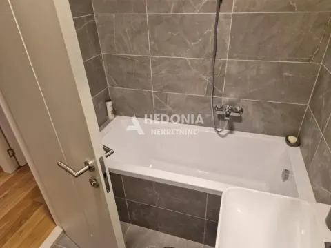 Bathroom equipped with a bathtub and grey ceramic tiles. - image 14