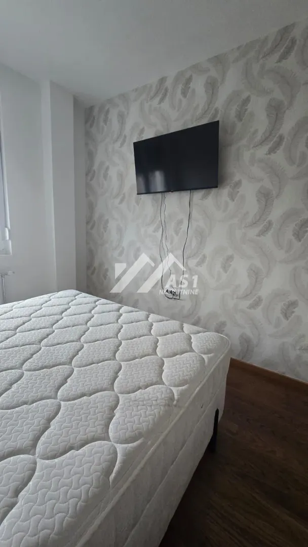 Spavaća soba sa bračnim krevetom i televizorom na zidu.