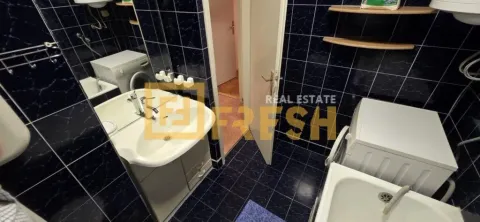 Kupatilo sa tamnim pločicama, umivaonikom i veš mašinom. - image 7