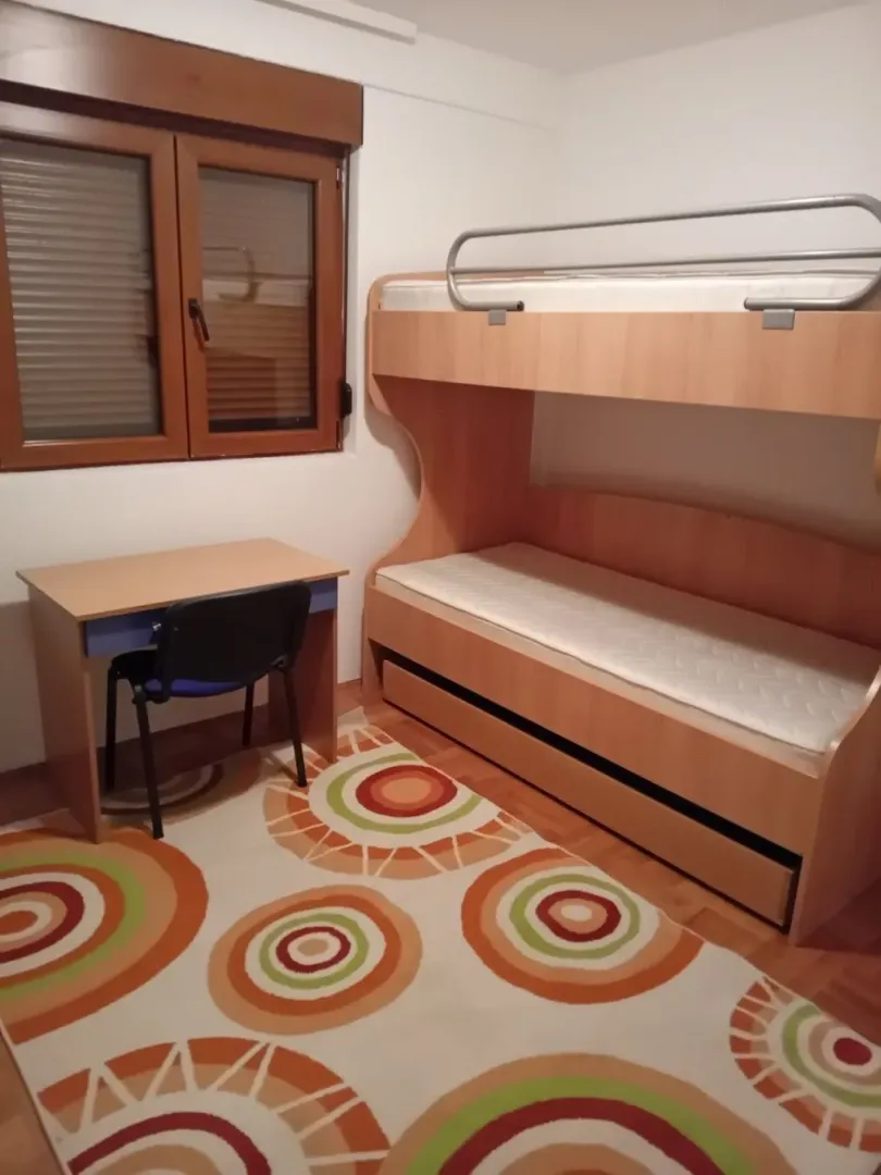 Children's bedroom with a bunk bed, desk, and window.