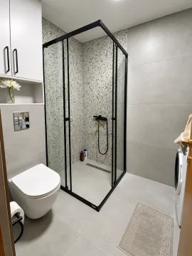 Savremeno opremljeno kupatilo sa tuš kabinom, konzolnom šoljom i veš mašinom. - image 7