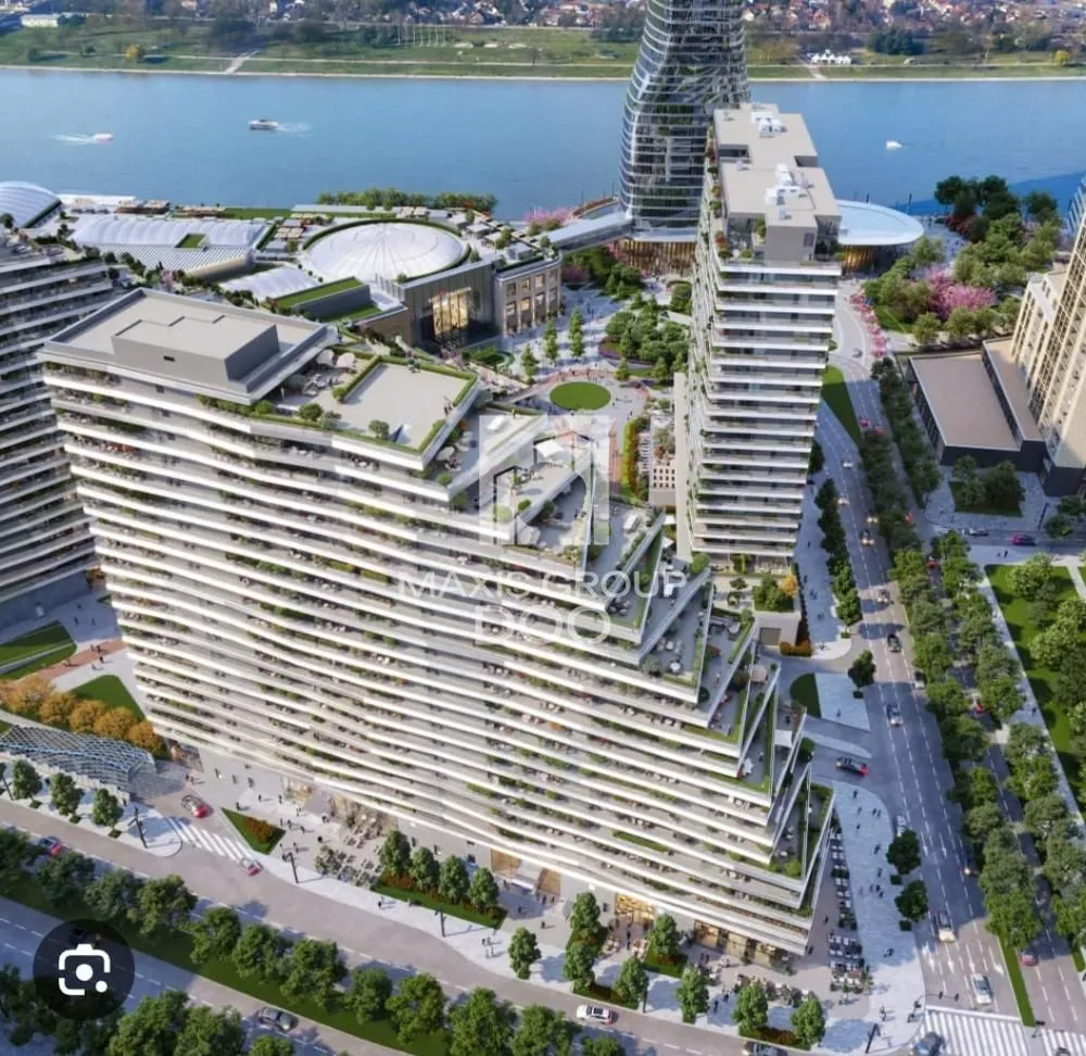 Pogled iz vazduha na moderne stambene zgrade sa uređenim dvorištem i rekom u pozadini.