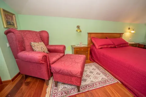 Bedroom with a double bed, an armchair, and wooden flooring. - image 20
