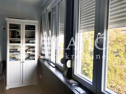 Living room with a white bookcase and large windows.