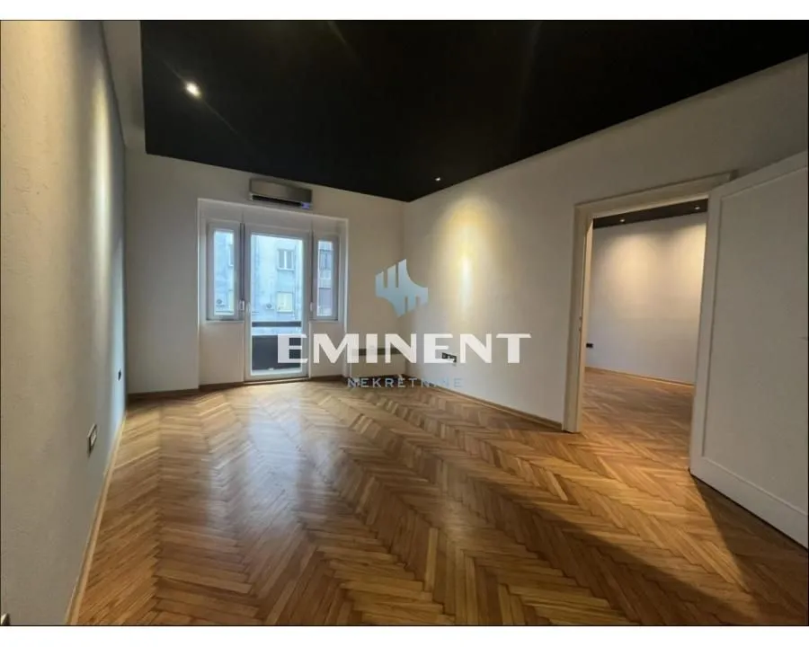 Empty room with hardwood flooring and a black ceiling.