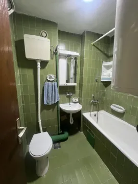 Kupatilo sa zelenim pločicama, kadom i toaletom. - image 5