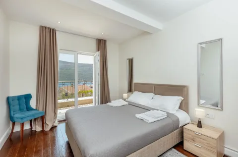 Svijetla spavaća soba sa bračnim krevetom, plavom foteljom i izlazom na balkon. - image 12