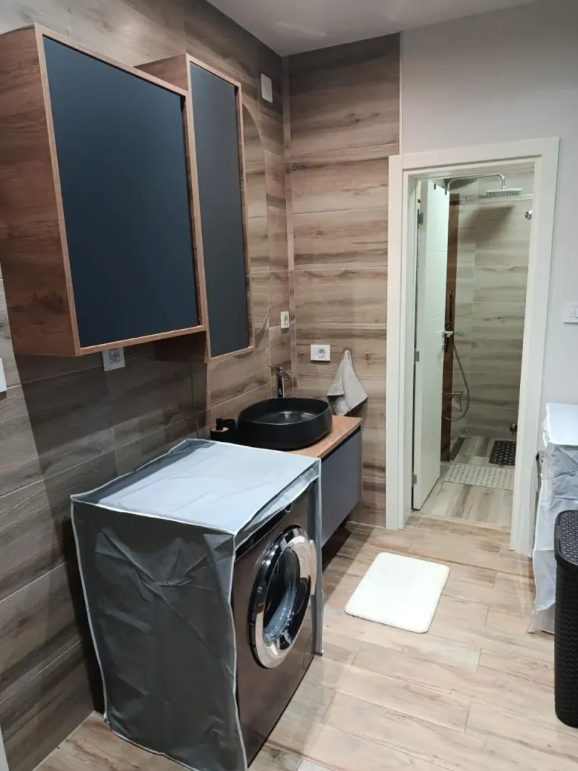 Moderno kupatilo sa umivaonikom, mašinom za veš i odvojenom tuš kabinom.
