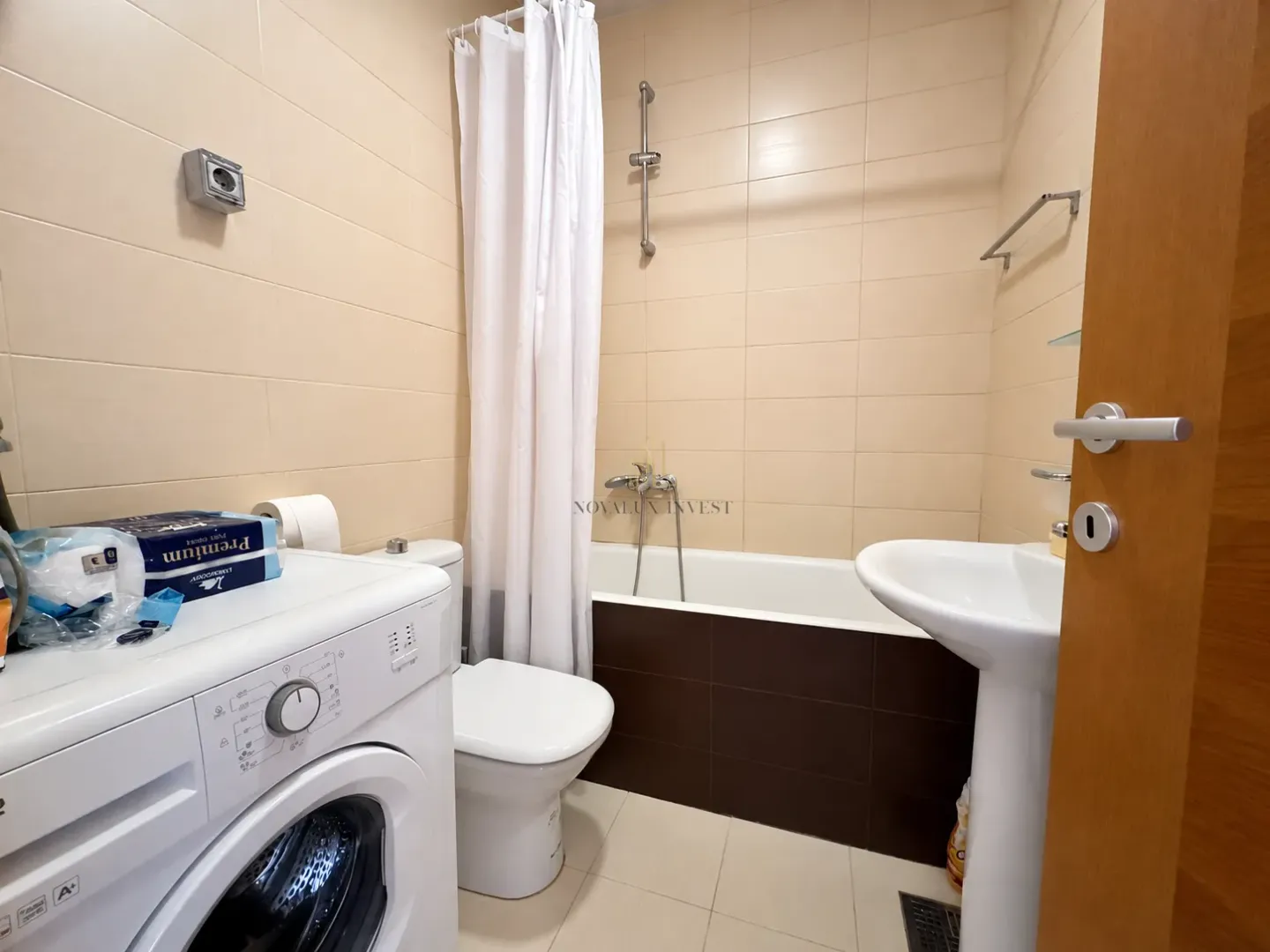 Kupatilo opremljeno kadom, umivaonikom, WC šoljom i veš mašinom.