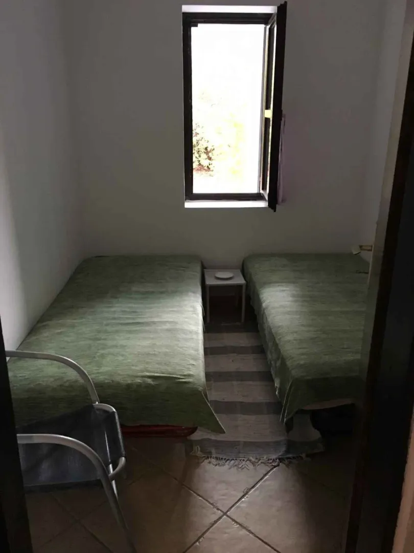 Mala spavaća soba sa dva singl kreveta i prozorom.