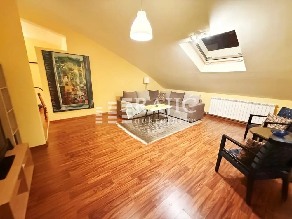 Attic living room with sofa set and wooden floor.