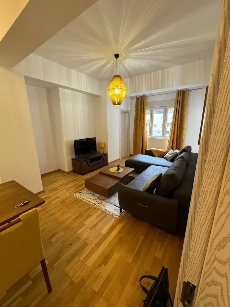 Comfortable living room with a sectional sofa, TV unit, and dining table.