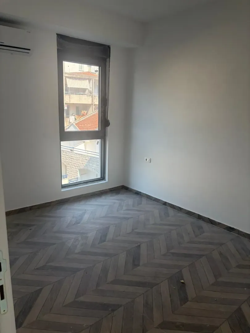 Prazna soba sa laminatom i prozorom.