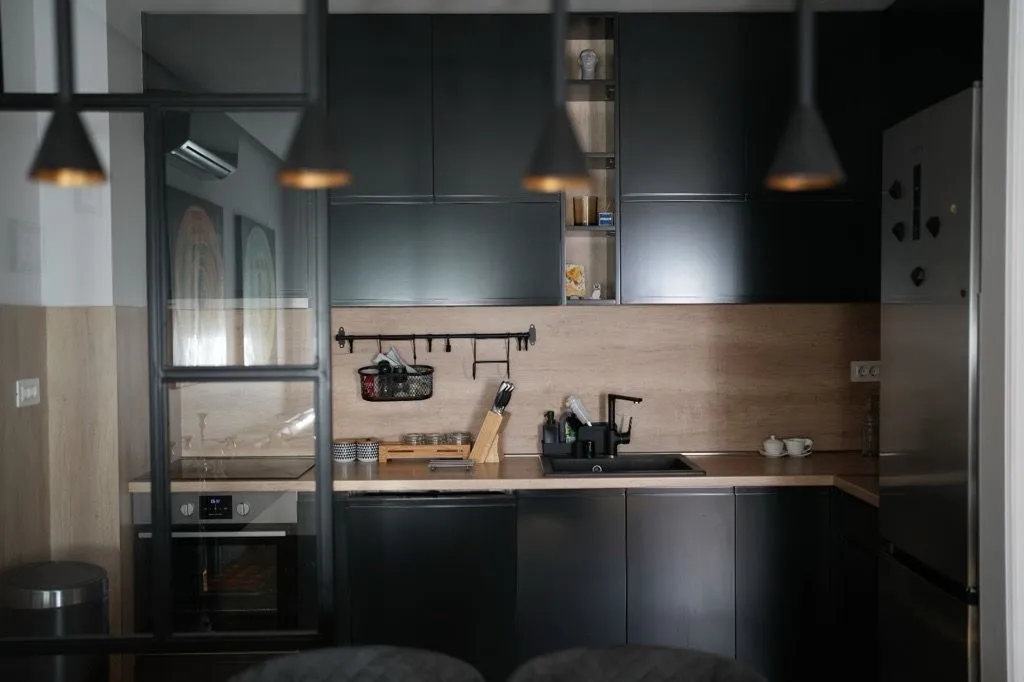 Modern kitchen with dark cabinets and wooden details.
