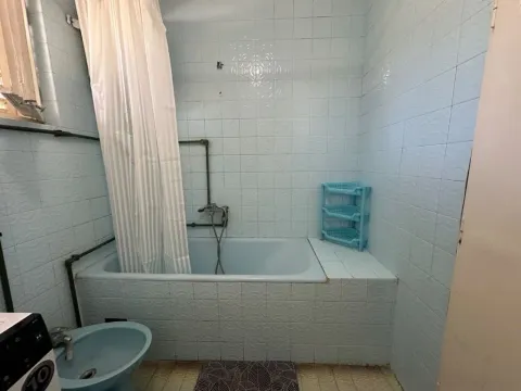Starije opremljeno kupatilo sa kadom i plavim pločicama. - image 8