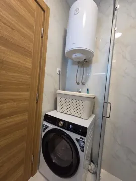 Bathroom with a washing machine, water heater, and shower cabin. - image 25