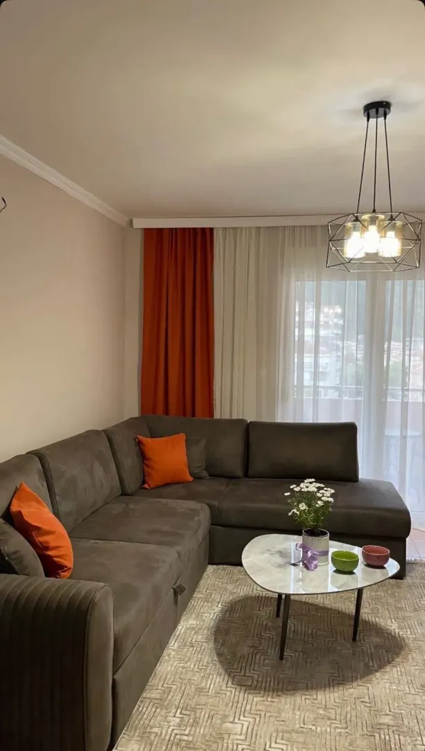 Living room with a corner sofa, coffee table, and modern chandelier.